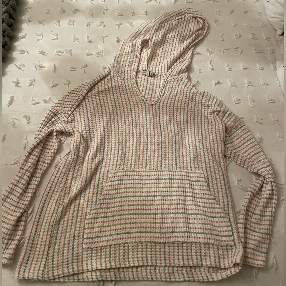 A cream colored light sweater with hints of pink and grey. Has pockets.
